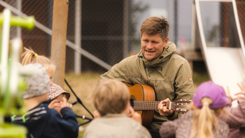 Mand spiller guitar for børn