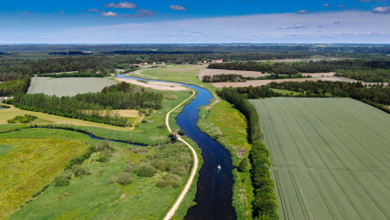 Luftfoto af å og sti gennem landskab