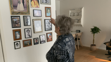 Ældre dame kigger på fotovæg i plejebolig