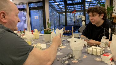 En beboer og en ung medarbejder spiller kort på et plejecenter