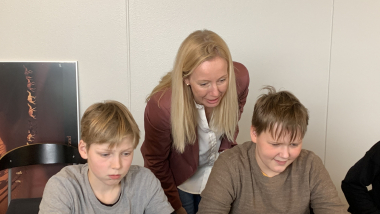 To elever får hjælp af en underviser ved deres computere