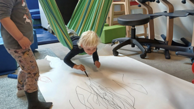 Vuggestuebørn tegner, mens de gynger.