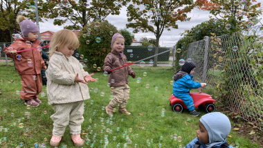 Børnene leger med sæbebobler i haven.