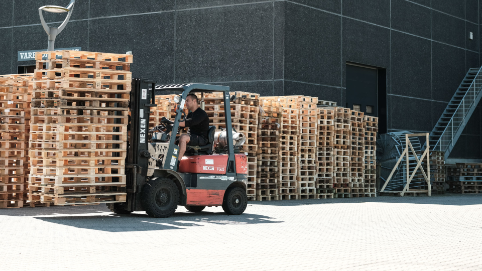 Paller fragtes af mand i gaffeltruck