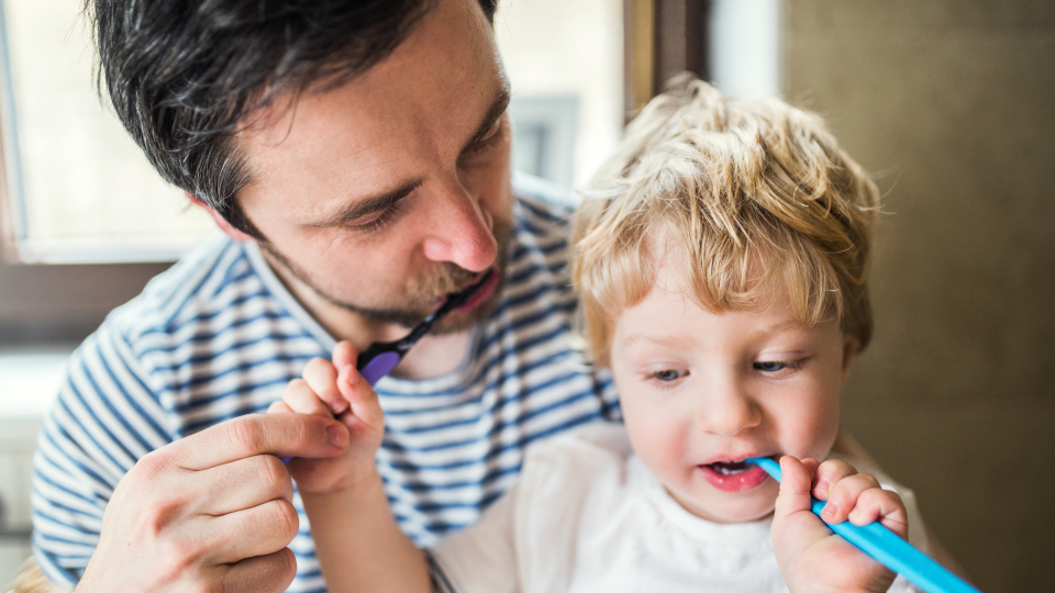 Far børster tænder på barn