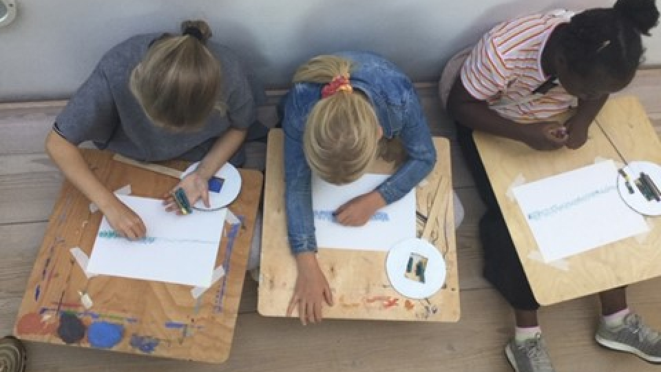 Tre elever tegner på papir