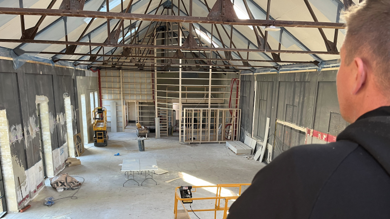 Mand kigger udover stor hal under renovering