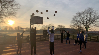 Elever spiller udendørs basket