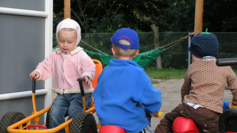 Tre børn på en legeplads i en børnehave