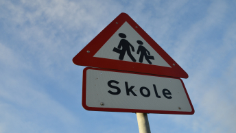 Trafikskilt ved skole med piktogram af børn og teksten "skole"
